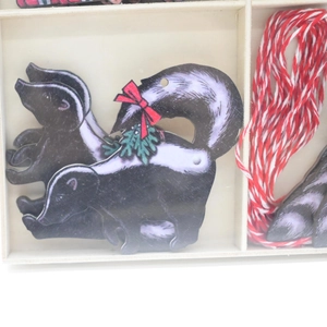Close-up of wooden skunk hanging ornaments with festive red bows and hanging ropes