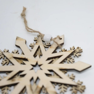 Detailed laser-cut wooden snowflake ornament with a rustic hemp rope and white bead accent