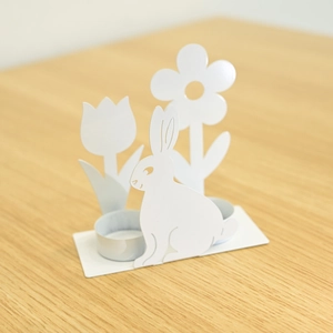 Nahaufnahme der weißen Hasen-Kerzenhalter mit Tulpen-Ausschnitten auf Holztisch
