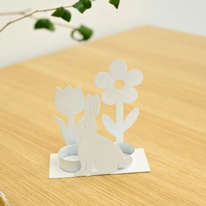 Detailansicht weißer Osterhasen-Kerzenhalter aus Eisen mit Tulpendekor auf Holztisch