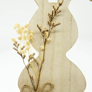 Macro detail of wooden Easter bunny with dried flowers and rustic jute rope bow