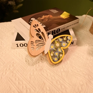 Détail d'un pendentif papillon en bois avec ailes ajourées et motif floral de marguerites