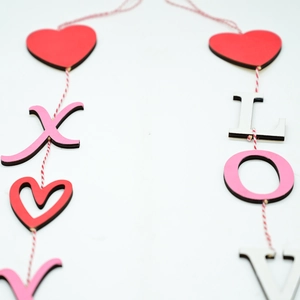 Detail of wooden LOVE and heart hanging decorations with red and white cotton string