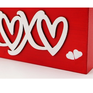 Detail shot of the red wooden XOXO ornament featuring white interlocking heart decorations