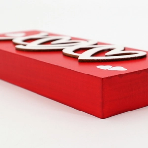 Detail view of red wooden Love block with heart accents for romantic home decor