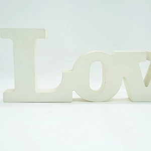 Close-up of white wooden LOVE letter sign with matte finish for home decor