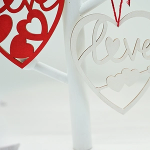 Close-up of heart-shaped wooden Love ornaments with red and white hollow designs