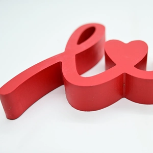 Close-up of the smooth red finish and side contour of a wooden 3D Love sign decoration