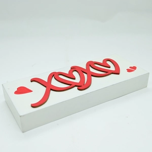 Detail view of wooden XOXO tabletop sign with 3D red letters and heart accents
