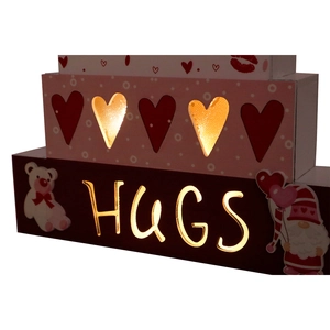 Détail de décoration étagée en bois avec LED et texte HUGS ajouré pour la Saint-Valentin