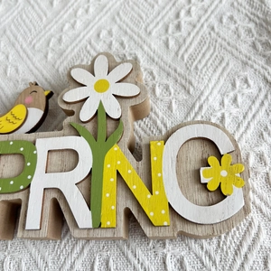 Nahaufnahme des Spring-Schriftzugs aus Holz mit Blumen und Vogel für die Tischdeko