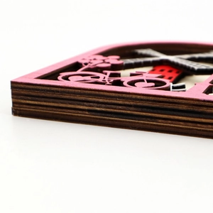 Detail of layered laser-cut wood ferris wheel decor showing pink frame and 3D depth