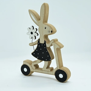 Detail of wooden Easter bunny on scooter with white flower and black polka dot dress