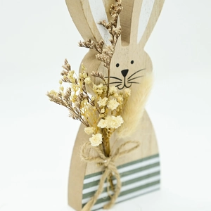 Detail of wooden Easter bunny with natural grain, dried flowers, and striped base ornament