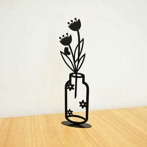 Detail of minimalist black metal flower vase silhouette with tulips and butterfly on desk