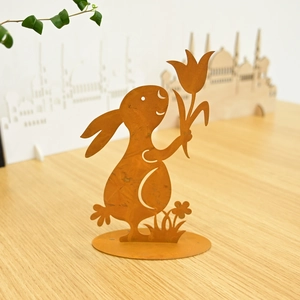 Detail of rusty metal Easter bunny ornament with tulip, standing on wooden surface