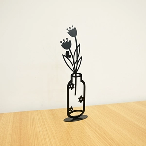 Detailed view of black metal tulip vase silhouette sculpture on a wooden surface