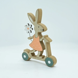Detailed view of a wooden bunny on a scooter with pink polka dot dress home decor