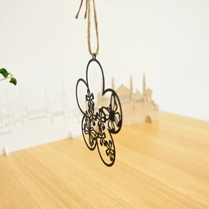 Detail view of a black cutout floral metal wreath ornament hanging by a rustic jute rope