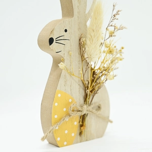 Detail of wooden Easter bunny ornament featuring dry flower bouquet and yellow polka dot egg