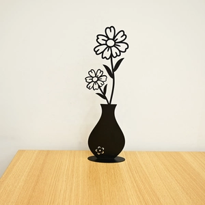 Detailed view of black metal wall art with minimalist floral silhouette on wood