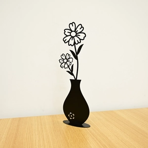 Detail of minimalist black metal sunflower sculpture in a vase on a wooden table