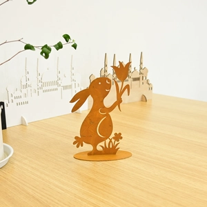 Detail of rusty metal Easter bunny silhouette with flower on wooden table decor