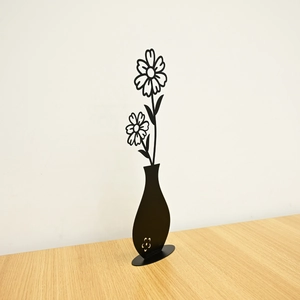 Detail of minimalist black metal flower sculptures in vase with oval base and matte finish
