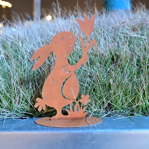 Rustic metal Easter bunny garden ornament with tulip cut-out on a grassy lawn