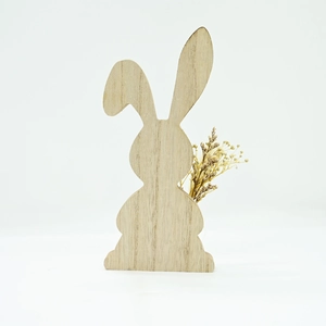 Detail of wooden Easter bunny ornament with natural wood grain and small dried flowers