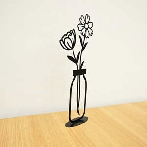 Detail of minimalist matte black metal flower sculpture with stable oval base for desk decor