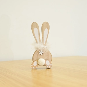Detailed close-up of a wooden bunny ornament with feather collar and fluffy tail