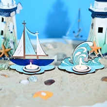 Detail of Mediterranean style sailboat and wave tea light holders on a beach setup