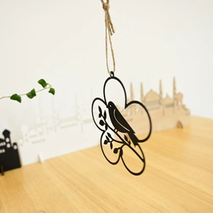 Detail of laser-cut metal wreath with birds silhouette hanging on natural jute rope
