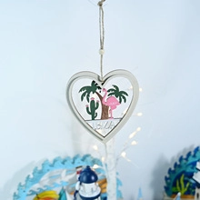 Detail view of heart-shaped wooden Aloha hanging sign with tropical flamingo and palm trees