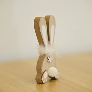 Detail of wooden bunny ornament with white feather collar and natural grain texture