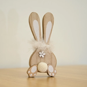 Detail of wooden Easter bunny with feather collar and pom-pom tail for home decor