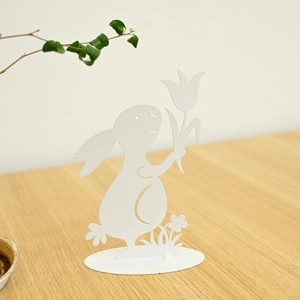 Detailed view of white metal Easter bunny statue with flower design on wooden surface