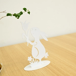 White metal Easter bunny decoration with a tulip detail on a rustic wooden tabletop