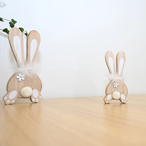 Detail of two wooden Easter bunnies with soft white feather collars and fluffy tails
