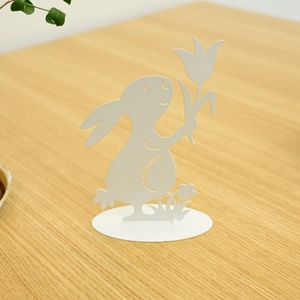 White metal Easter bunny figurine with tulip on wooden table close-up garden decor