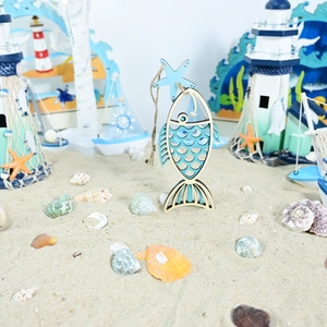 Detail of laser-cut fish hanging ornament with starfish on a sandy beach background
