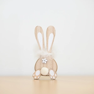 Detail of wooden Easter bunny with fur collar and white pom-pom tail on a desk