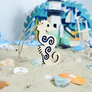 Detail of wooden seahorse pendant with blue laser-cut swirls on a sandy nautical decor