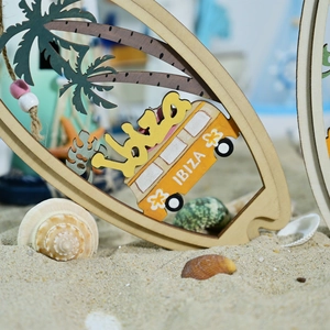 Detail of wooden surfboard ornament with Ibiza car design placed in beach sand with shells