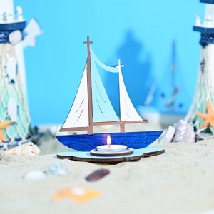 Détail d'un bougeoir voilier marin en bois avec coquillages et étoiles de mer sur sable