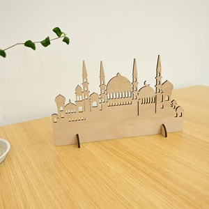 Close-up of laser-cut wooden mosque silhouette ornament with crescent moon on a wooden desk