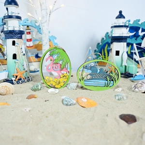 Detail of wooden ocean-themed wall hanging with flamingo and palm leaves on sand
