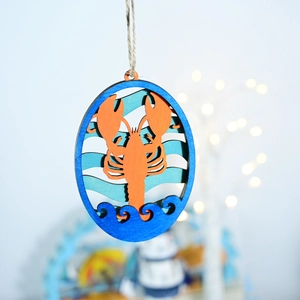 Detail of laser-cut layered wooden lobster ornament with blue ocean waves and rope