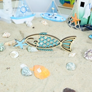 Detailed view of ocean style wooden fish decor with starfish on a sandy beach setting
